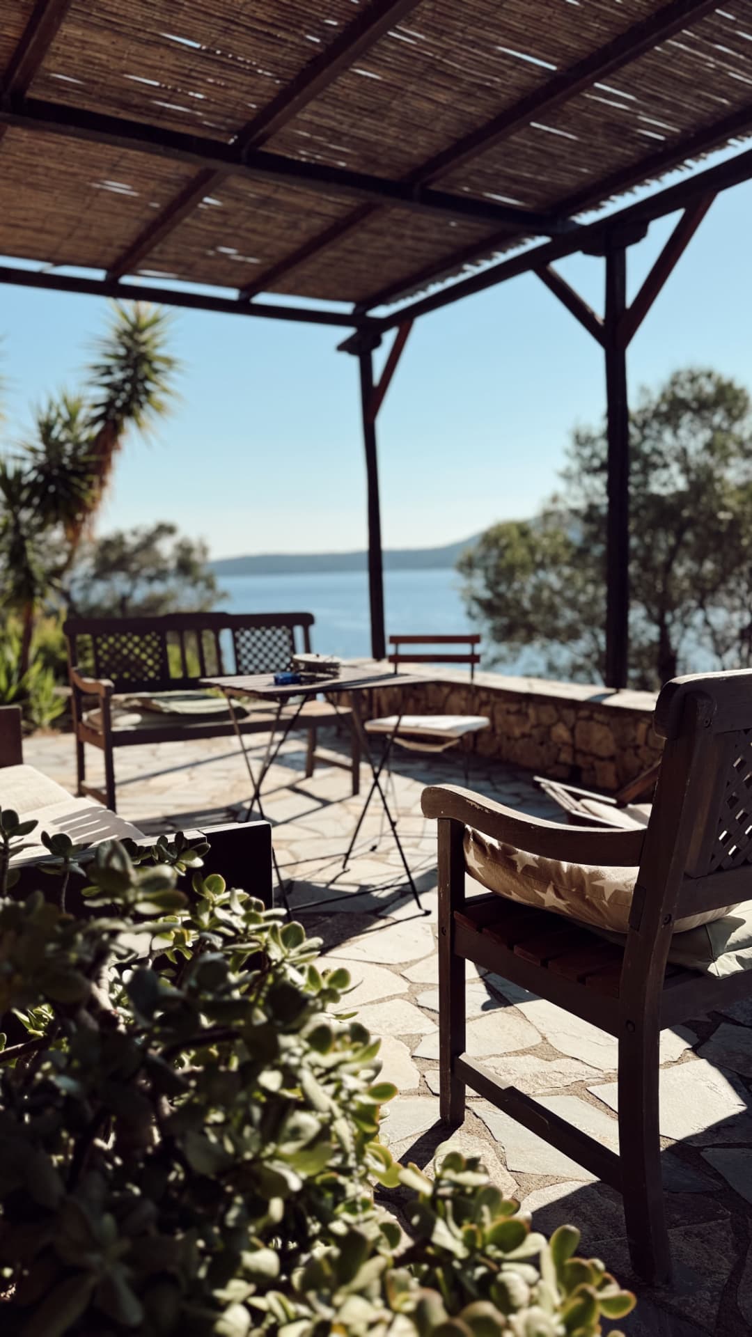 Covered ground-floor terrace with reed pergola, seating and a sea view