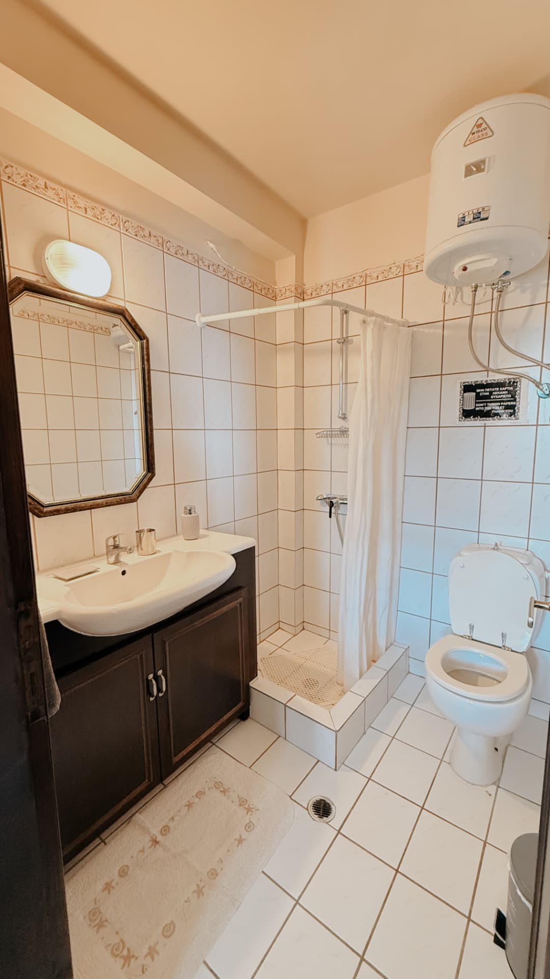 Ground-floor tiled bathroom with shower, sink and mirror