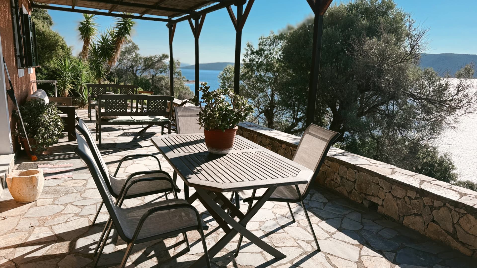 Ground-floor terrace with dining table, potted plants and a sea view