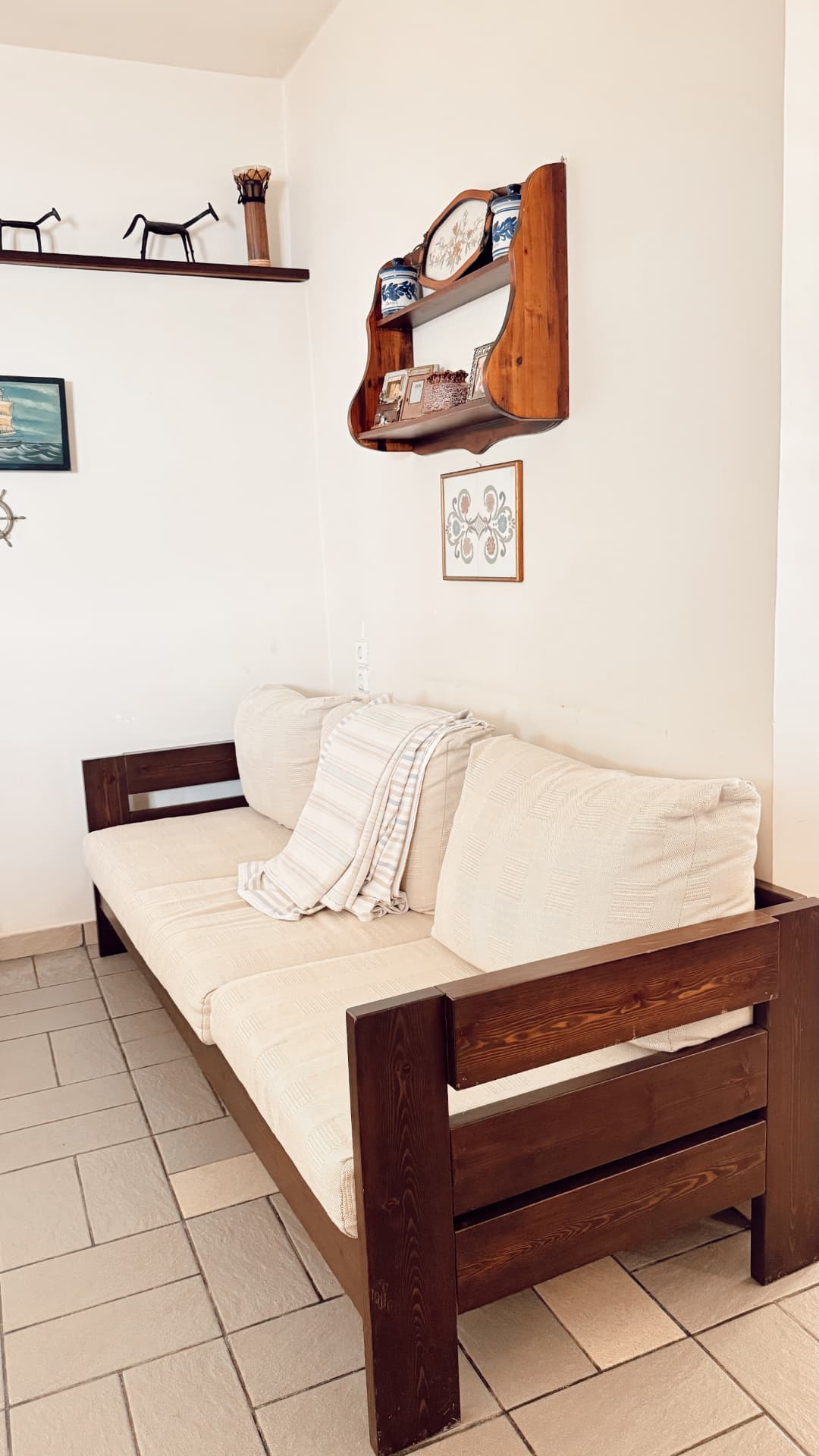 Ground-floor daybed with cream covers beside traditional wooden shelving
