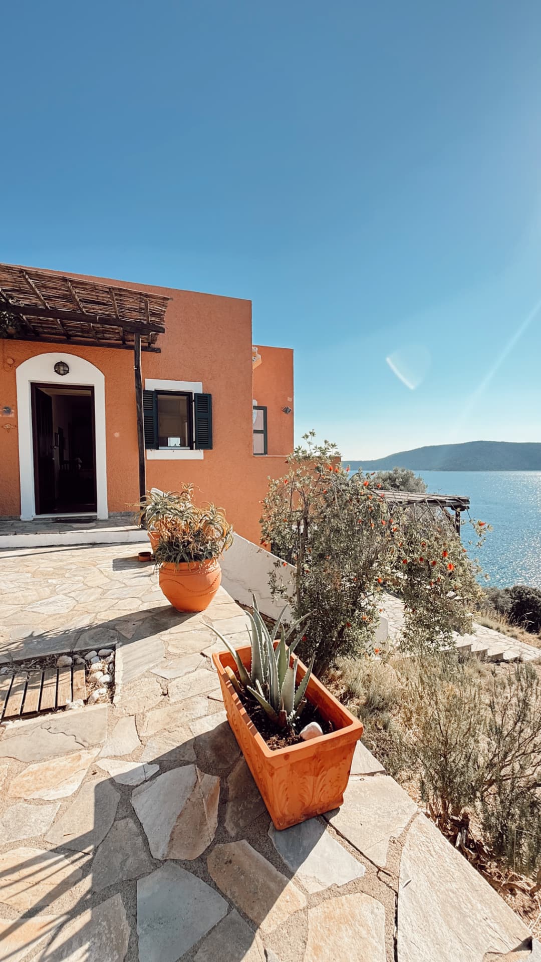 Sun-warmed terracotta facade with stone paving and a sea view