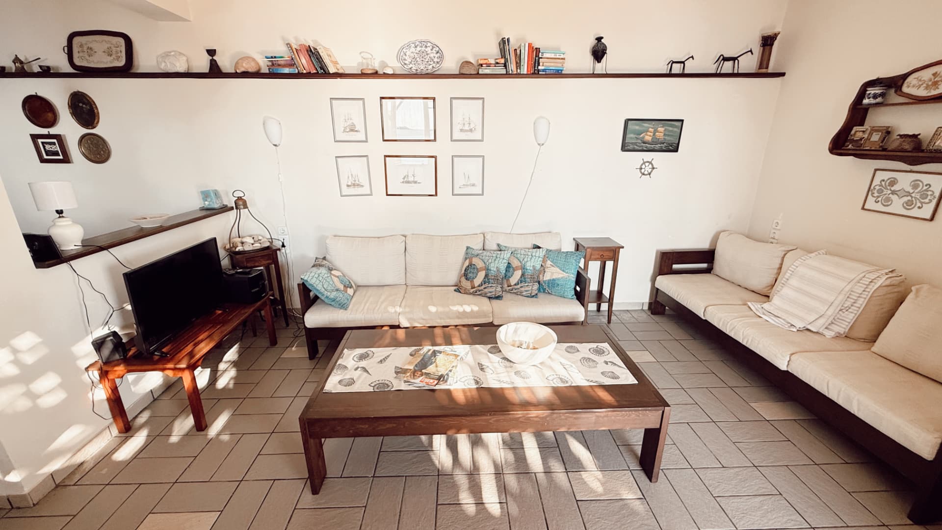 Ground-floor living room with cream sofas, nautical art and a coffee table
