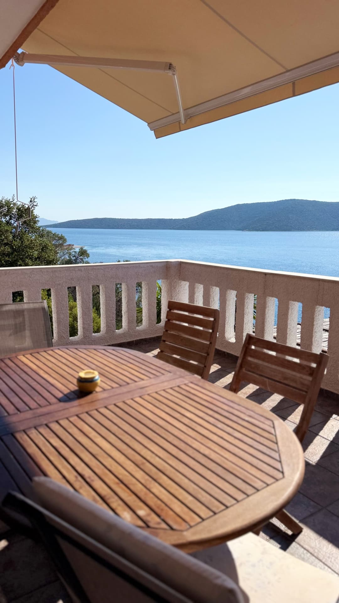 Balcony dining table set above a wide blue sea view